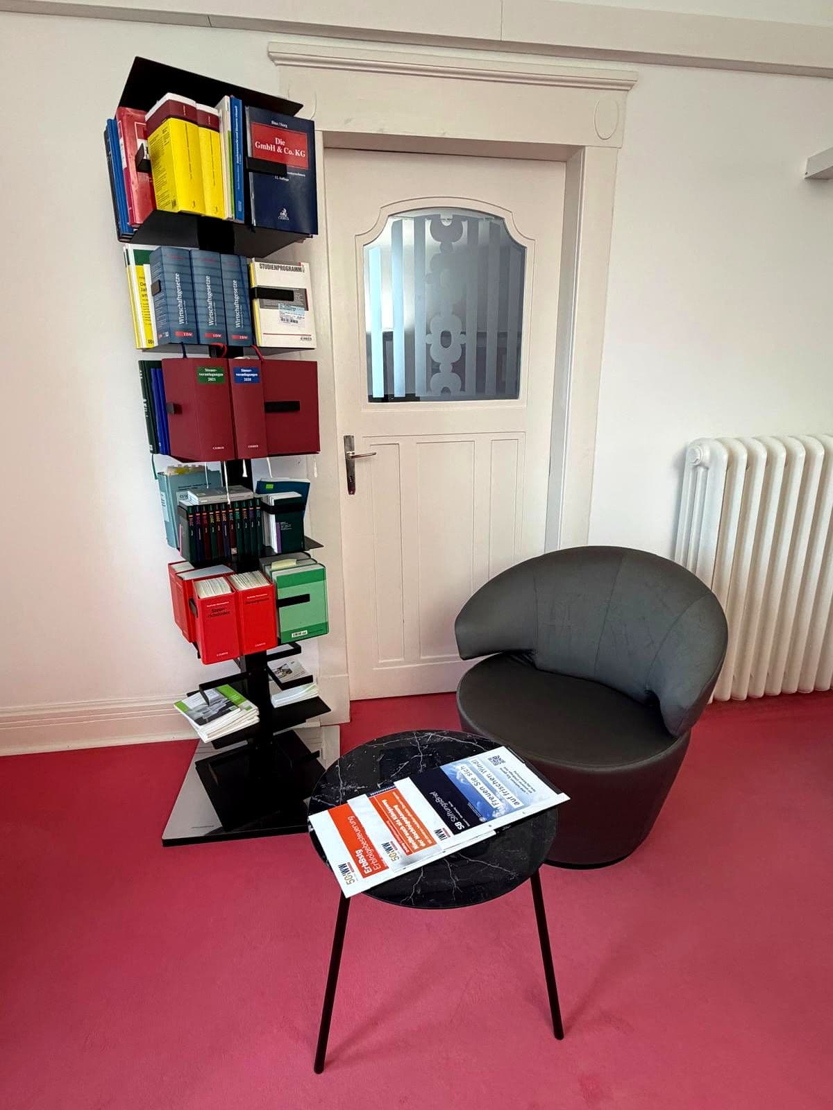 Bücherregal mit Fachliteratur und Sessel im Wartebereich